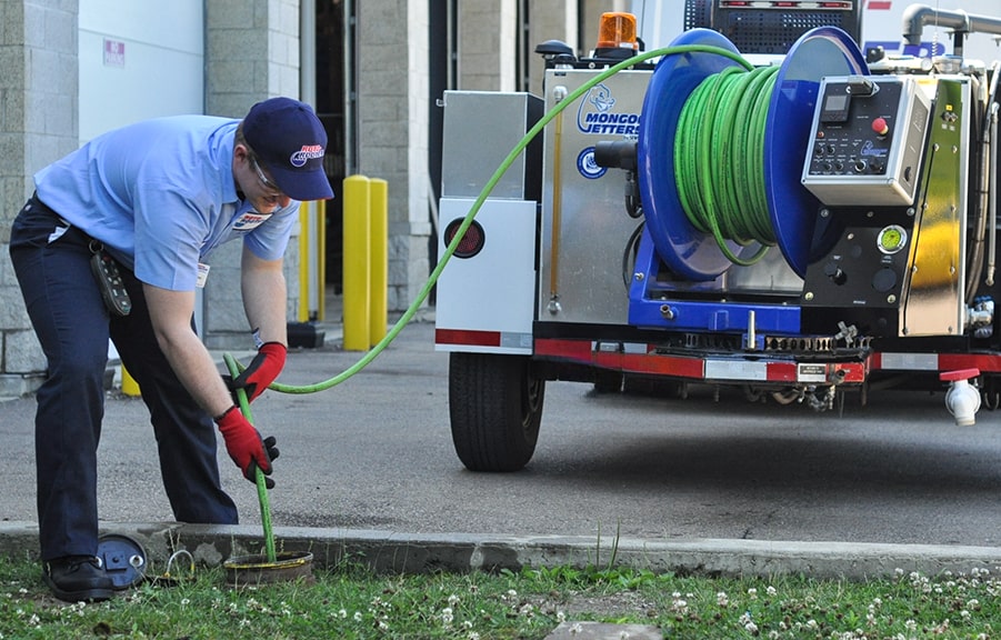 Employee clearing sewer backup caused by clogged sewer line