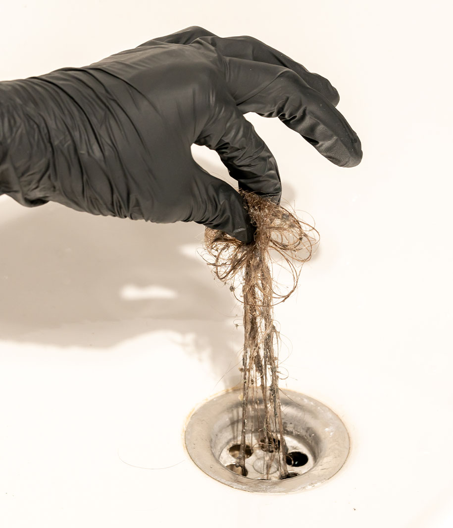 employee pulling hair out of drain